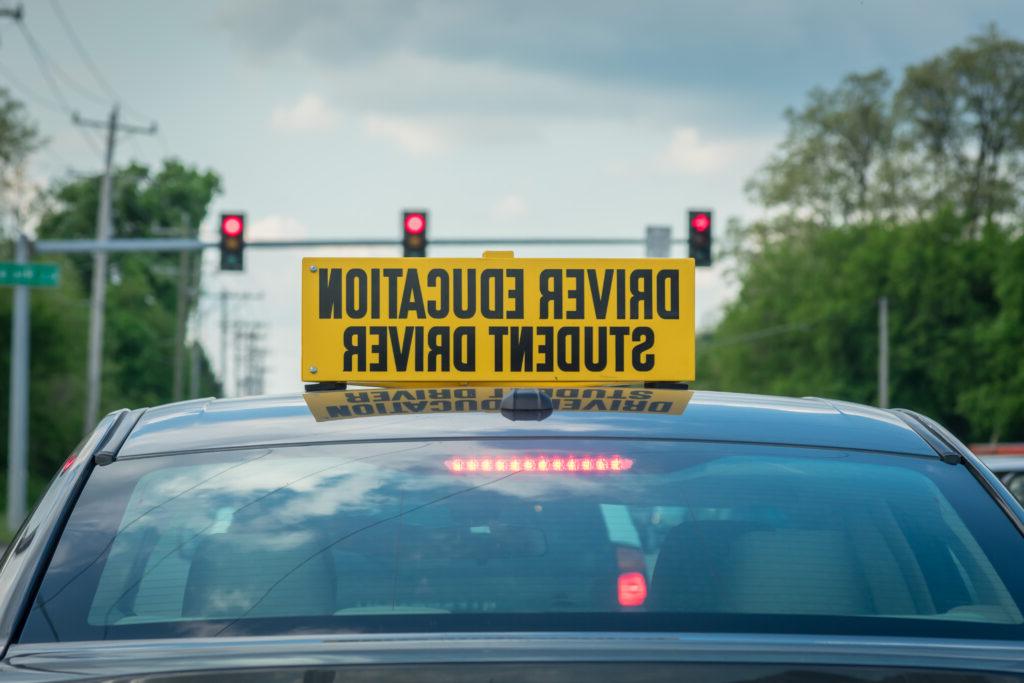 Student driver sign on top of car at stoplight